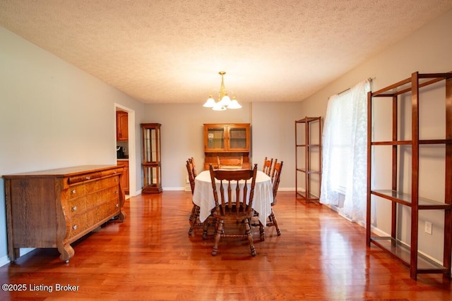 dining area with hardwood / wood-style flooring, a textured ceiling, and a chandelier