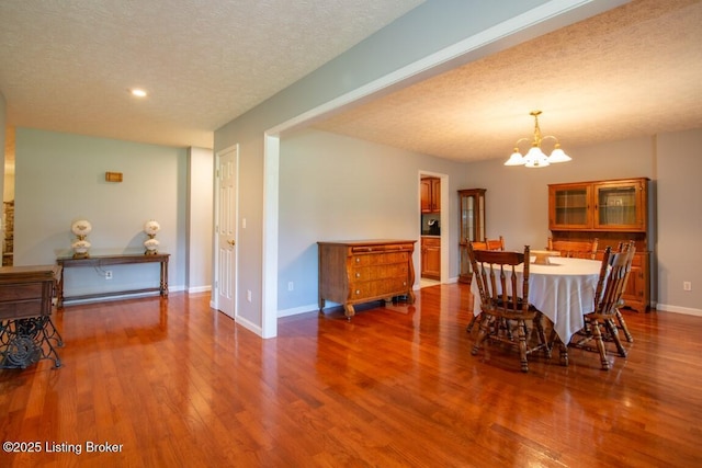 dining room with a textured ceiling, a chandelier, and wood-type flooring