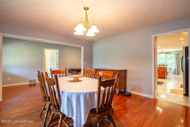 dining room with a textured ceiling, an inviting chandelier, and hardwood / wood-style flooring