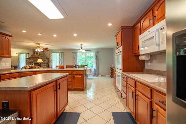 kitchen with sink, a center island, white appliances, light tile patterned floors, and kitchen peninsula