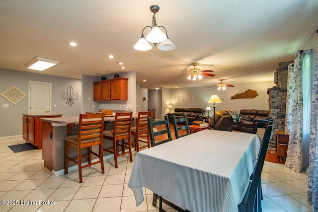 tiled dining space with a textured ceiling and ceiling fan