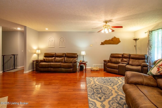 living room featuring a textured ceiling, ceiling fan, and hardwood / wood-style flooring