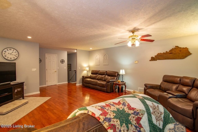 living room with a textured ceiling, ceiling fan, and hardwood / wood-style flooring