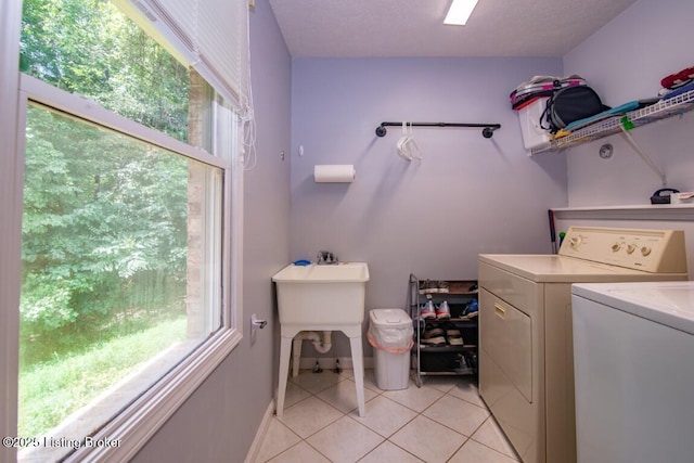 laundry area featuring a textured ceiling, light tile patterned floors, and separate washer and dryer