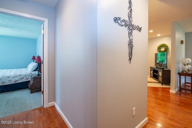 hallway with a textured ceiling and hardwood / wood-style floors