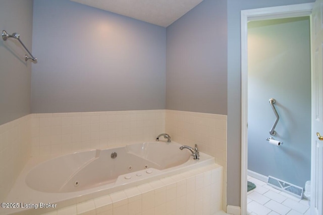 bathroom with tile patterned floors and tiled tub