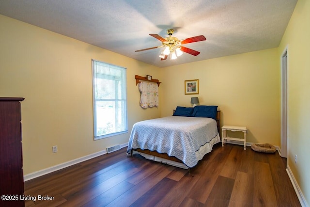 bedroom with ceiling fan, dark hardwood / wood-style flooring, and a textured ceiling