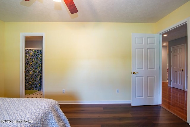 bedroom with a walk in closet, ceiling fan, and dark wood-type flooring