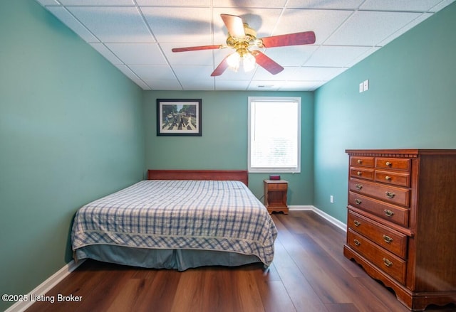 bedroom featuring ceiling fan, a paneled ceiling, and dark wood-type flooring