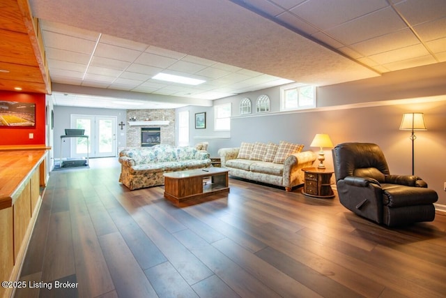 living room with dark hardwood / wood-style flooring, a fireplace, and a drop ceiling