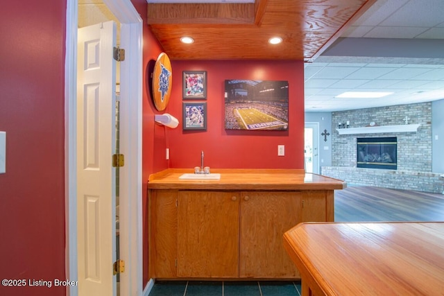 bar featuring sink, a brick fireplace, and dark tile patterned flooring