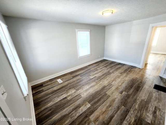 unfurnished room with dark wood-type flooring and a textured ceiling