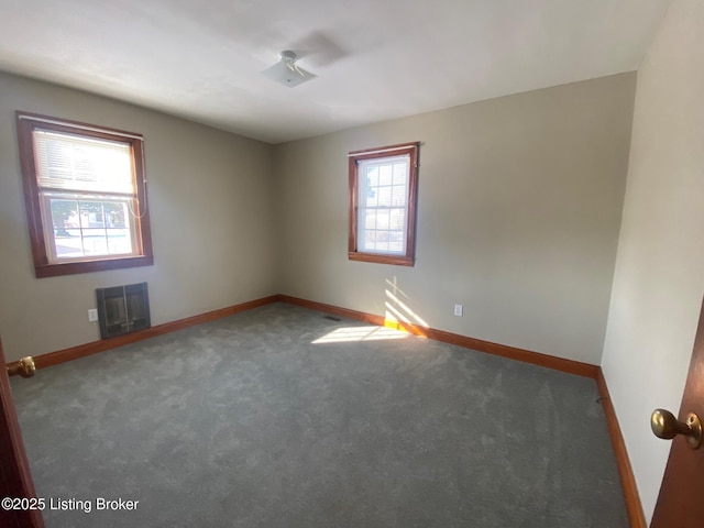 carpeted spare room with heating unit and a healthy amount of sunlight