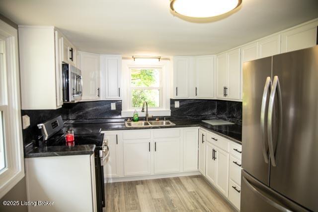 kitchen featuring stainless steel appliances, white cabinets, sink, and light wood-type flooring