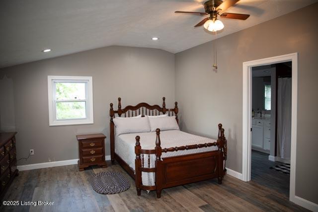 bedroom featuring ceiling fan, connected bathroom, lofted ceiling, and dark hardwood / wood-style floors