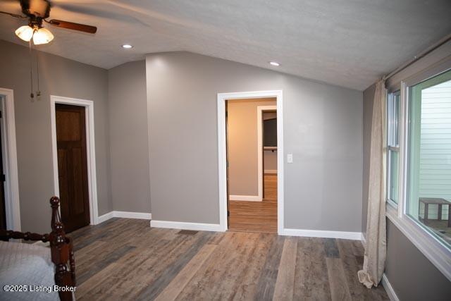 empty room with ceiling fan, dark hardwood / wood-style flooring, and lofted ceiling