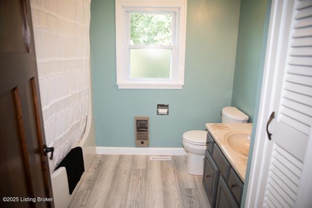 bathroom featuring toilet, hardwood / wood-style flooring, heating unit, and vanity