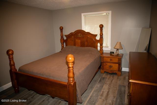 bedroom with a textured ceiling and dark hardwood / wood-style floors