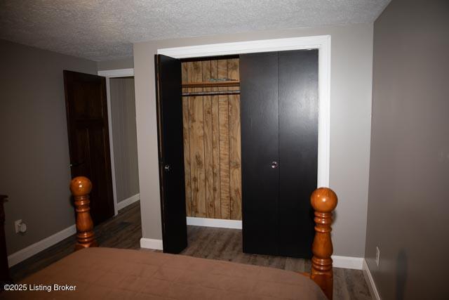 bedroom featuring a textured ceiling, a closet, and dark hardwood / wood-style flooring