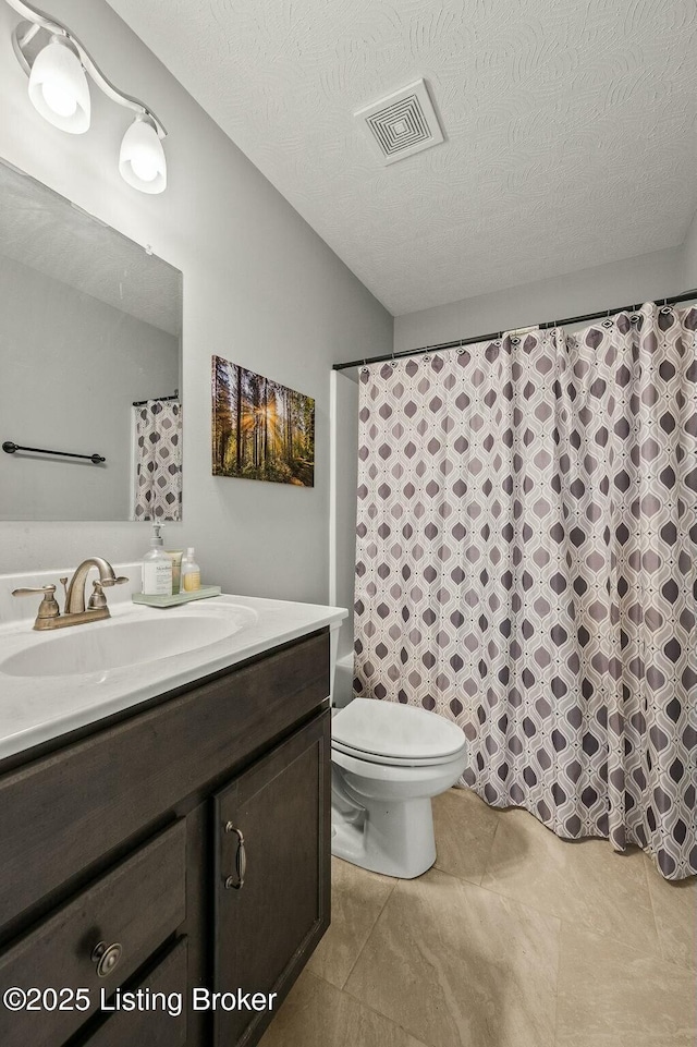 bathroom with a textured ceiling, toilet, and vanity