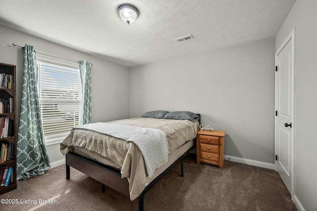 bedroom with a textured ceiling and dark colored carpet