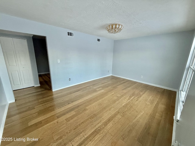 spare room with a textured ceiling and hardwood / wood-style floors