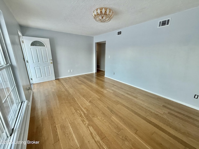 empty room with a textured ceiling and light hardwood / wood-style floors