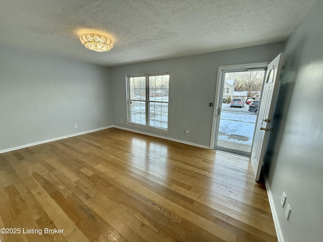 unfurnished room with a textured ceiling, hardwood / wood-style floors, and plenty of natural light