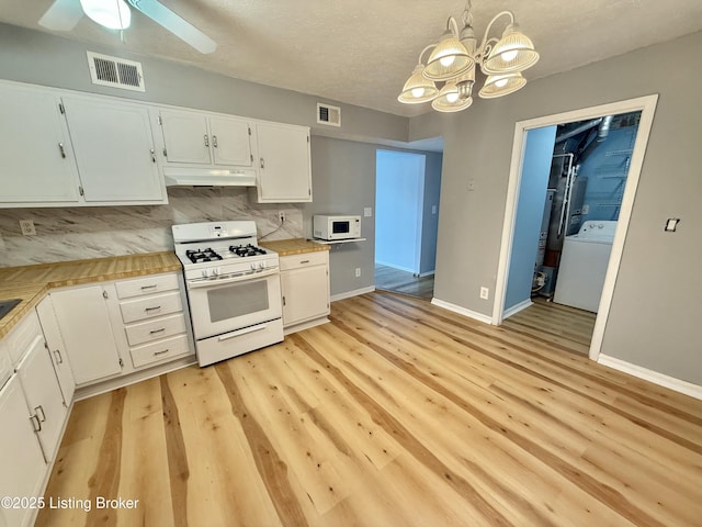 kitchen with washer / clothes dryer, white appliances, white cabinetry, and pendant lighting