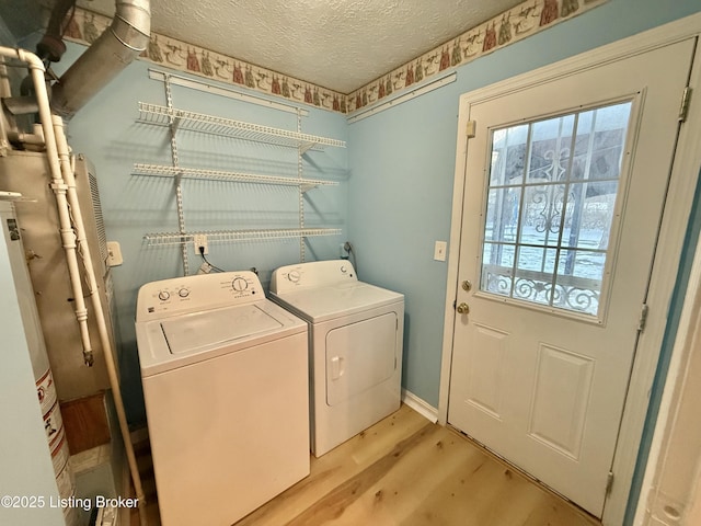 laundry room featuring a textured ceiling, washing machine and dryer, light wood-type flooring, and gas water heater