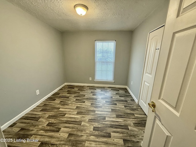 empty room with a textured ceiling and dark hardwood / wood-style flooring