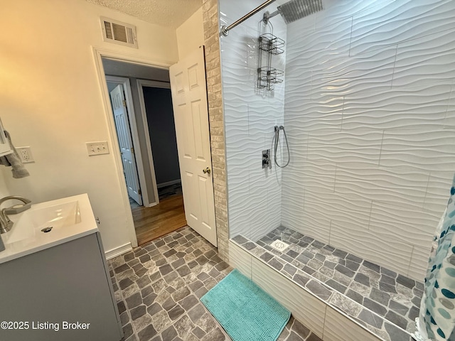 bathroom with curtained shower, vanity, and a textured ceiling