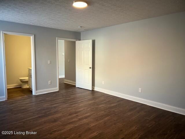 unfurnished bedroom featuring dark wood-type flooring, connected bathroom, and a textured ceiling