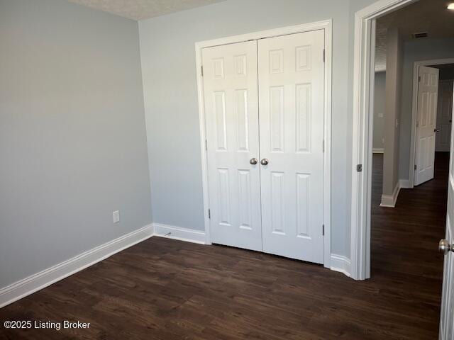 unfurnished bedroom with a closet and dark hardwood / wood-style flooring