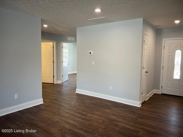 foyer entrance featuring a textured ceiling and dark wood-type flooring