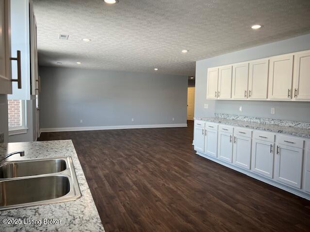 kitchen featuring white cabinetry, dark hardwood / wood-style floors, light stone countertops, a textured ceiling, and sink