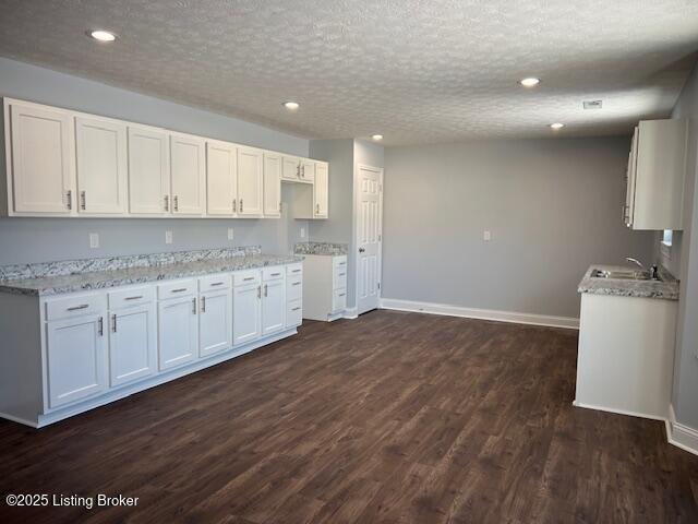 kitchen featuring sink, a textured ceiling, white cabinets, and dark hardwood / wood-style floors