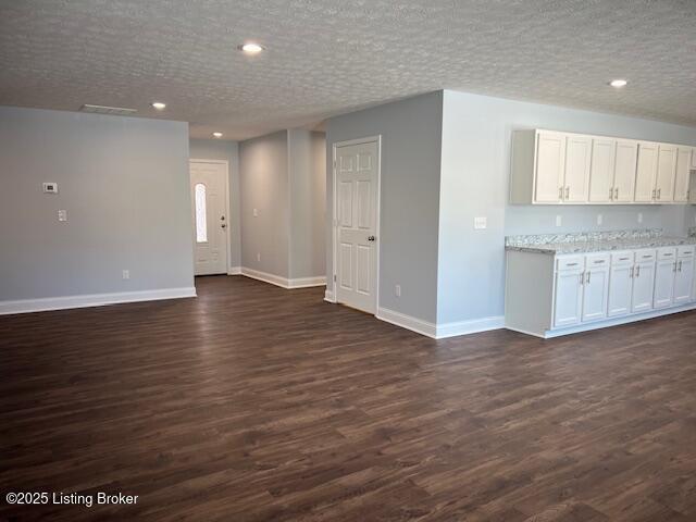 unfurnished living room featuring a textured ceiling and dark hardwood / wood-style floors