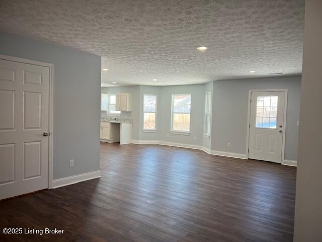 unfurnished living room featuring a textured ceiling and dark wood-type flooring