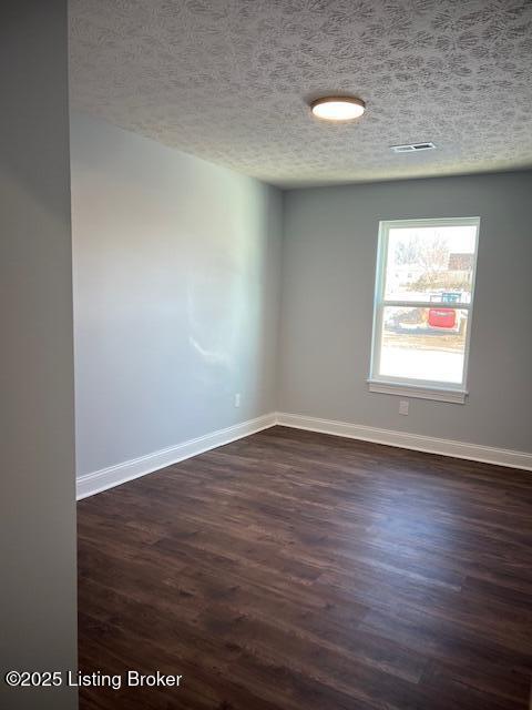 empty room with a textured ceiling and dark wood-type flooring