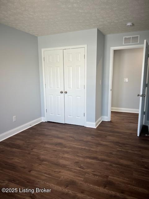 unfurnished bedroom featuring a closet, dark hardwood / wood-style flooring, and a textured ceiling