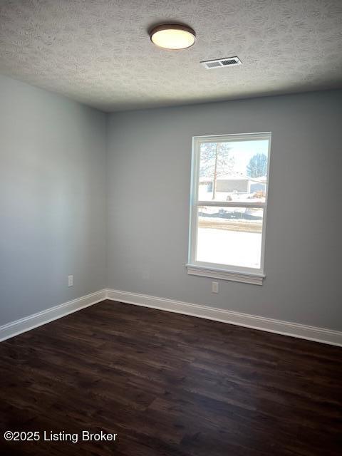 unfurnished room featuring dark wood-type flooring and a textured ceiling