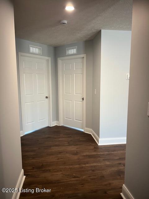 hall with a textured ceiling and dark hardwood / wood-style floors