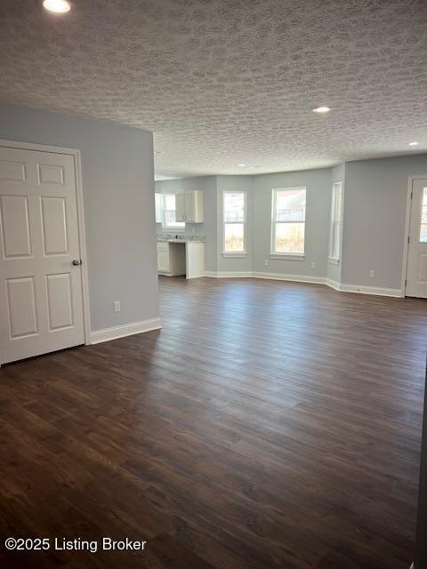 unfurnished living room with a textured ceiling and dark hardwood / wood-style flooring