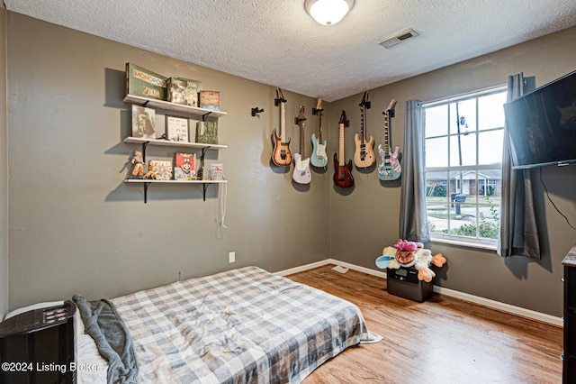 bedroom with a textured ceiling and hardwood / wood-style flooring