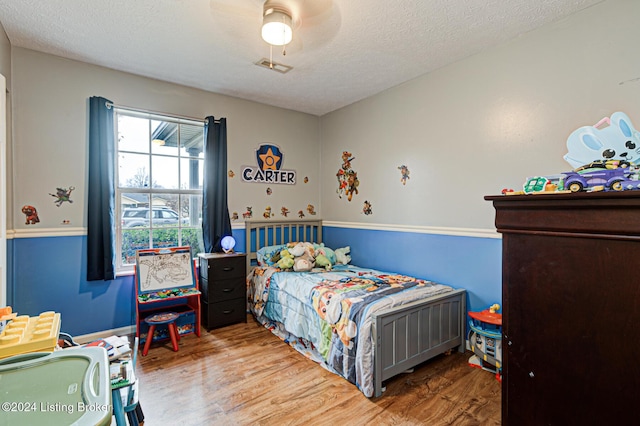 bedroom with ceiling fan, a textured ceiling, and hardwood / wood-style flooring