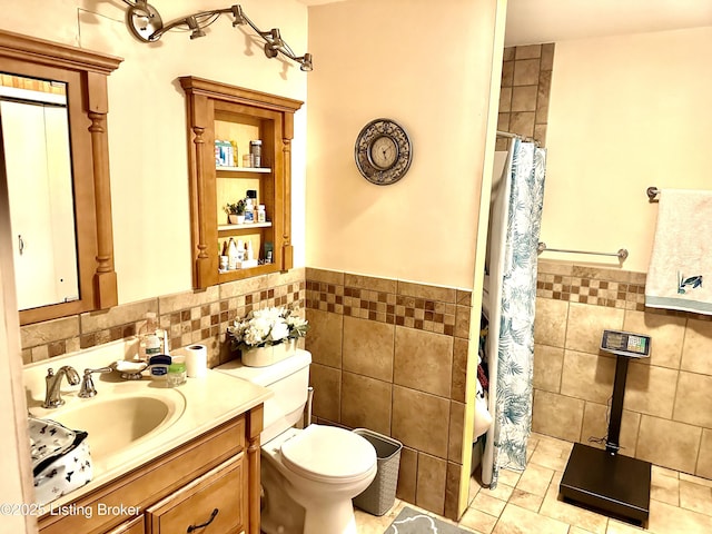 bathroom with toilet, a shower with shower curtain, tile patterned floors, vanity, and tile walls