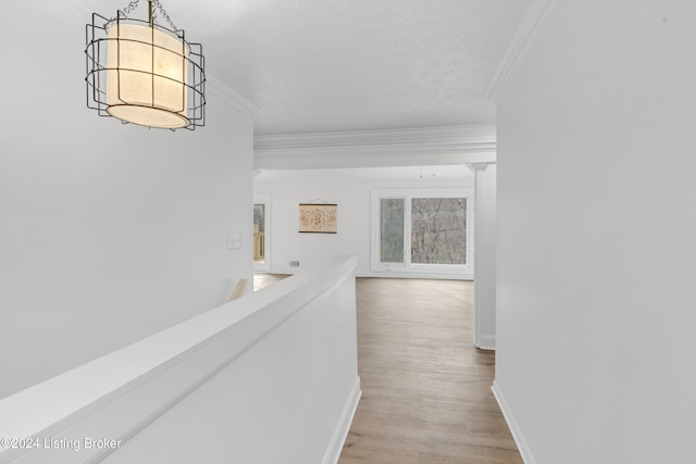 hall featuring ornamental molding, light hardwood / wood-style flooring, an inviting chandelier, and a textured ceiling