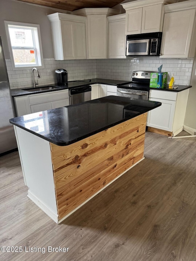 kitchen featuring white cabinetry, sink, a center island, stainless steel appliances, and light hardwood / wood-style flooring