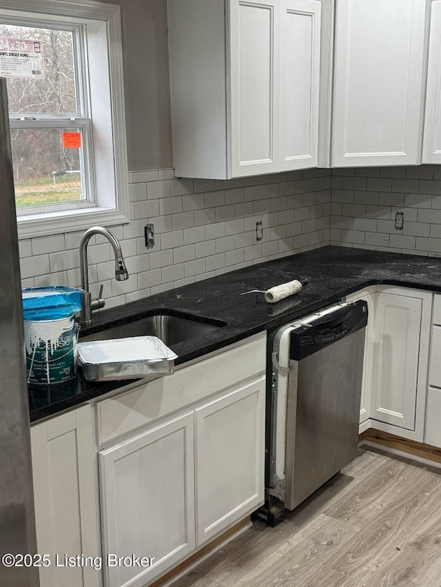 kitchen with stainless steel dishwasher, sink, and white cabinetry